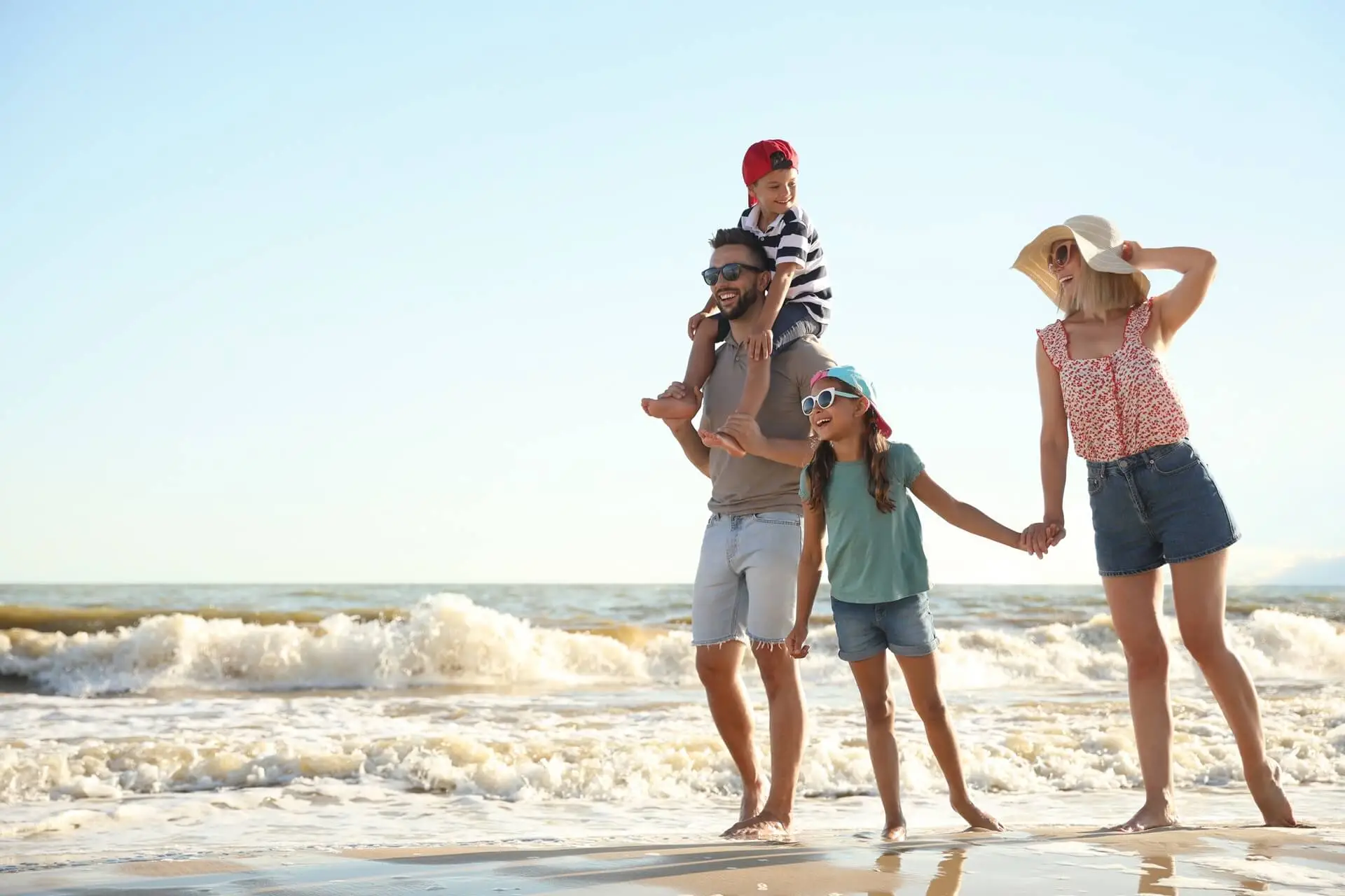 Eine Familie spaziert fröhlich am Strand entlang.