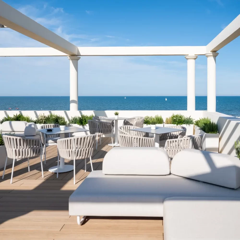 A rooftop terrace with seating overlooking the ocean under a clear blue sky.