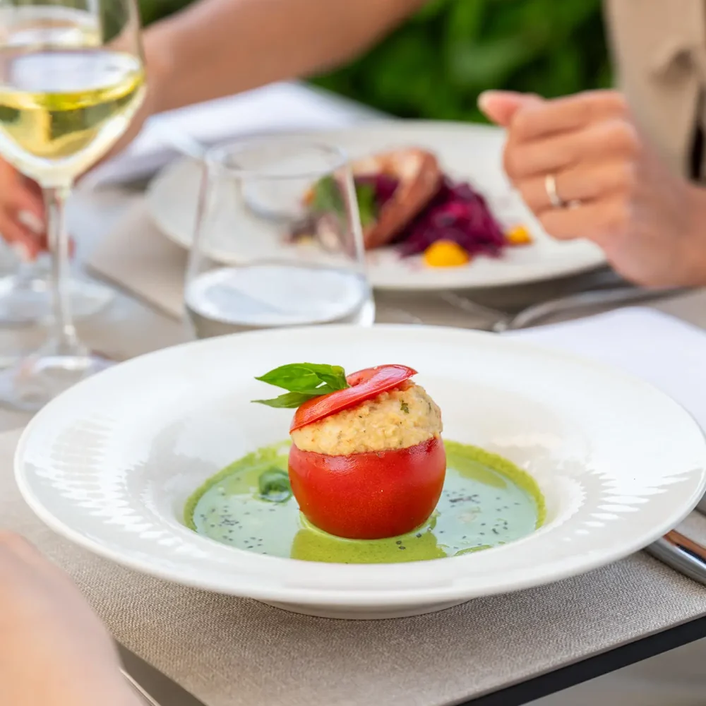 Eine gefüllte Tomate auf einer grünen Sauce wird in einem Restaurant serviert.