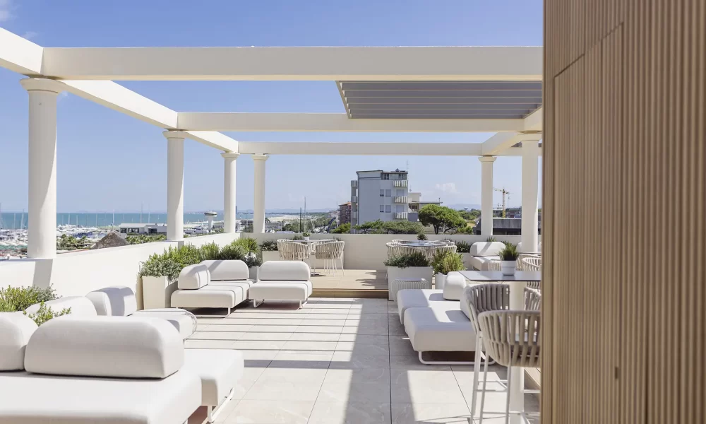 Terrasse moderne et ensoleillée avec pergola et vue sur la mer.