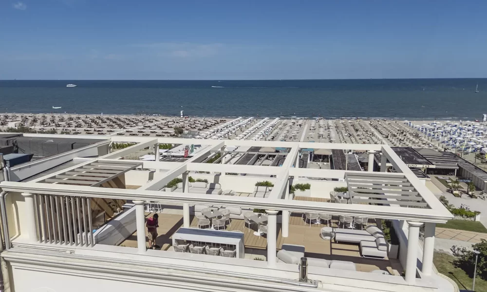 Vue d'une terrasse avec vue sur la plage et la mer par une journée ensoleillée.