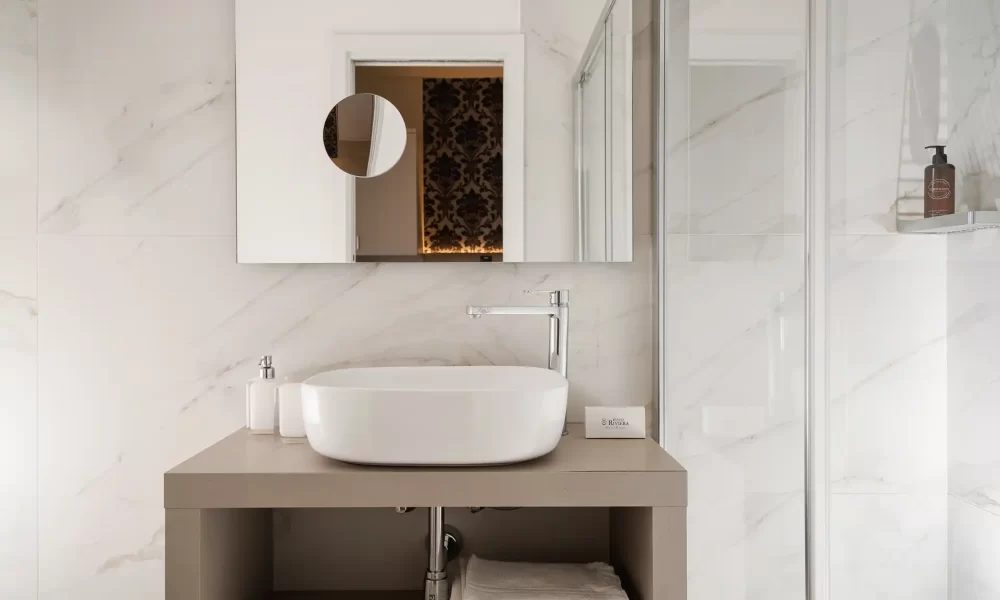 Salle de bain moderne avec lavabo design, miroir mural et cabine de douche.