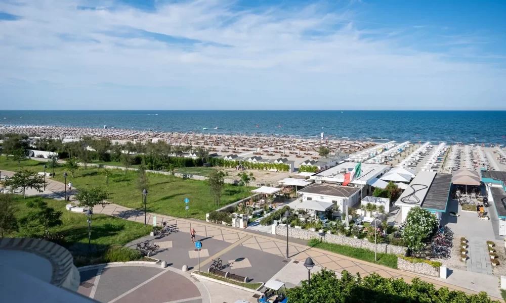Strand mit Reihen von Sonnenschirmen und einem Blick auf das Meer bei klarem Himmel.