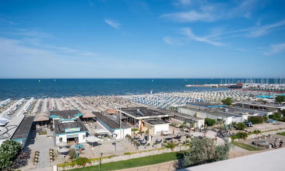 Strand mit Sonnenschirmen und Liegen an einem sonnigen Tag am Meer.